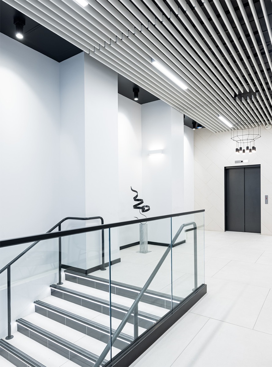 Black cylinder ceiling lights and cylinder pendant lights illuminate a modern office lobby.