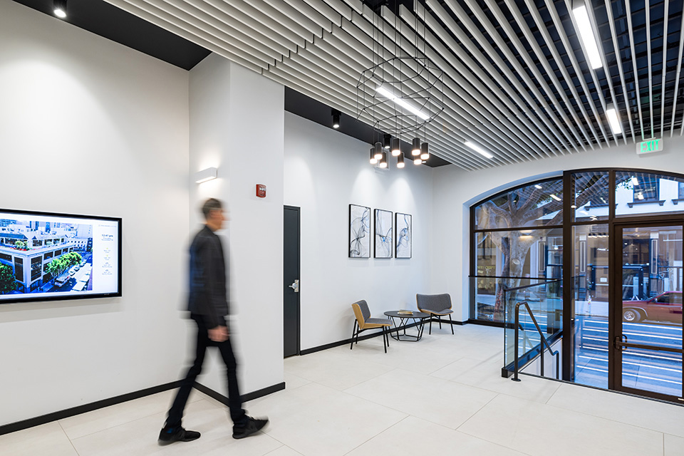 An office lobby features a distinctive pendant light, cylinder downlights and linear recessed lights 