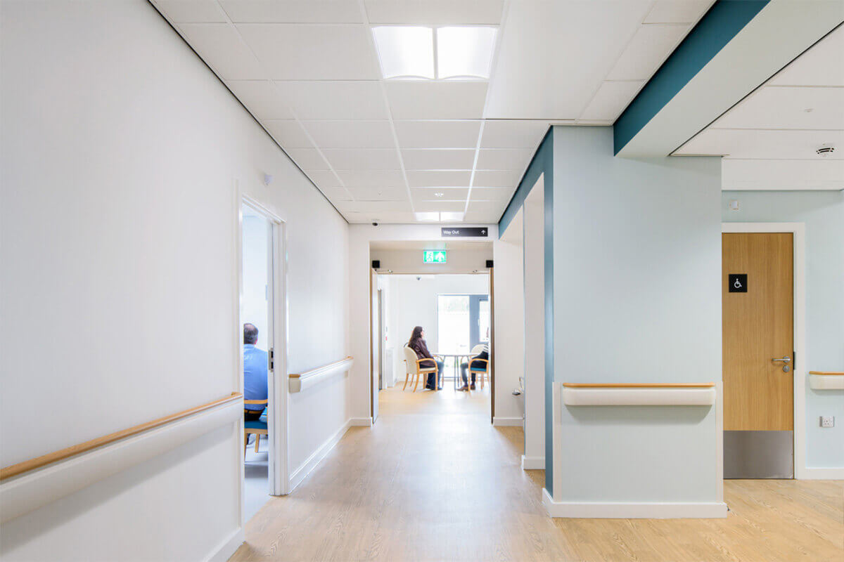 Troffer lights with a vertical diffuser lens light a hospital hallway with indirect downlight to reduce glare