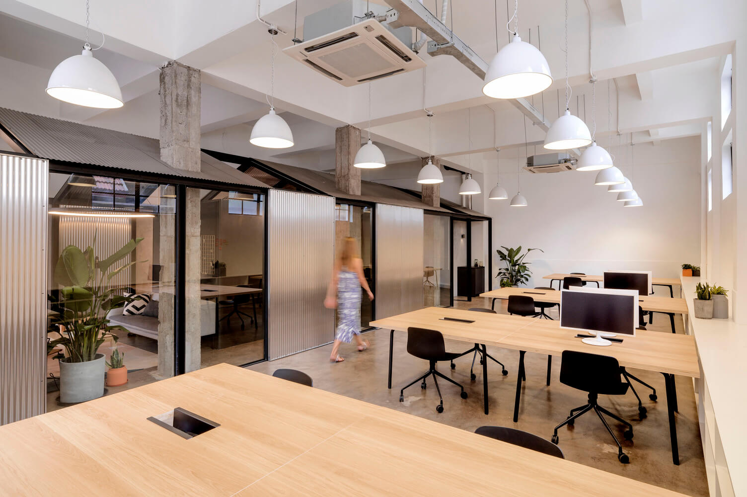 White dome industrial high bay LED lights hang from the ceiling in a contemporary office