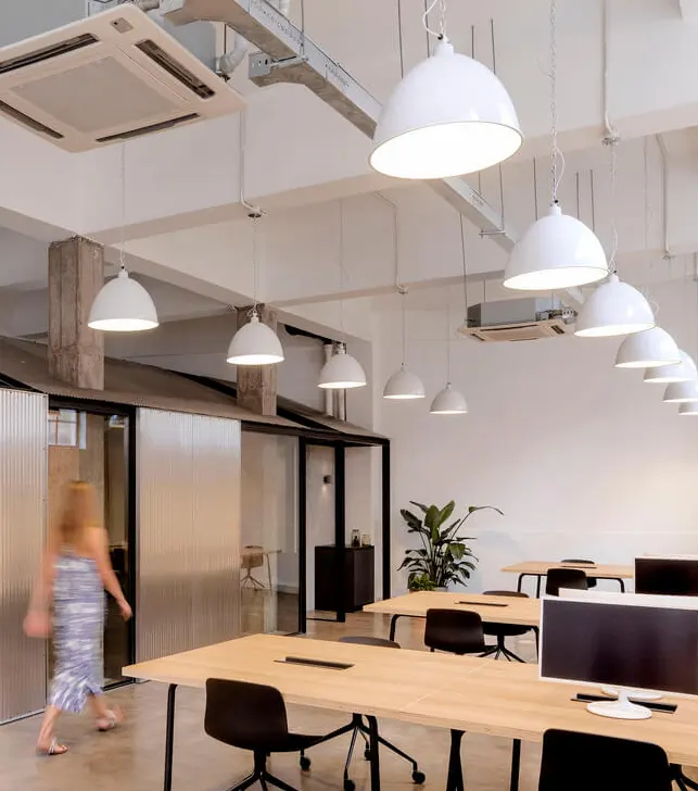 White industrial dome high bay lights provide general lighting for offices in a converted warehouse space.