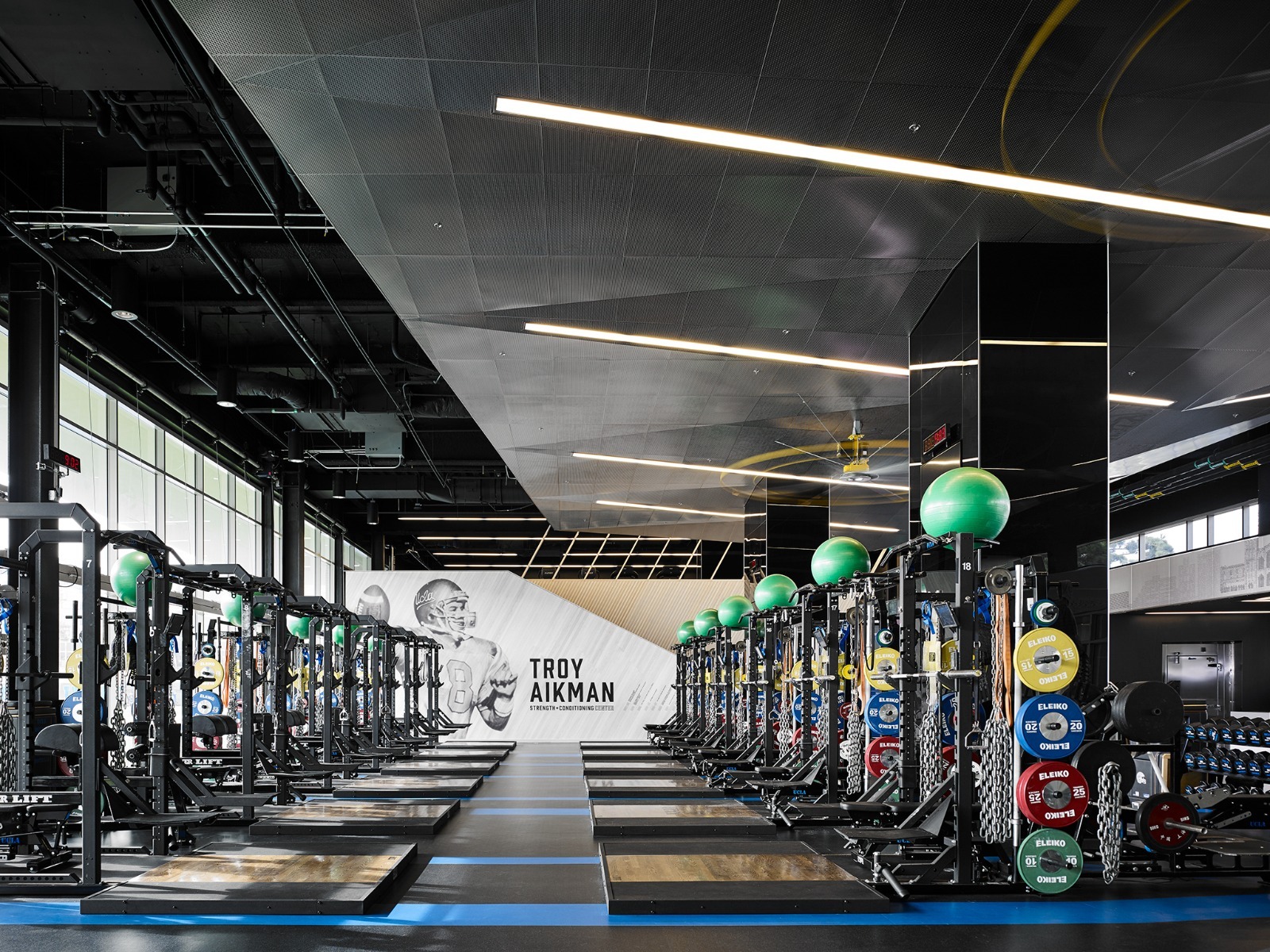 Linear recessed lights provide general lighting in a gym above weight lifting stations.