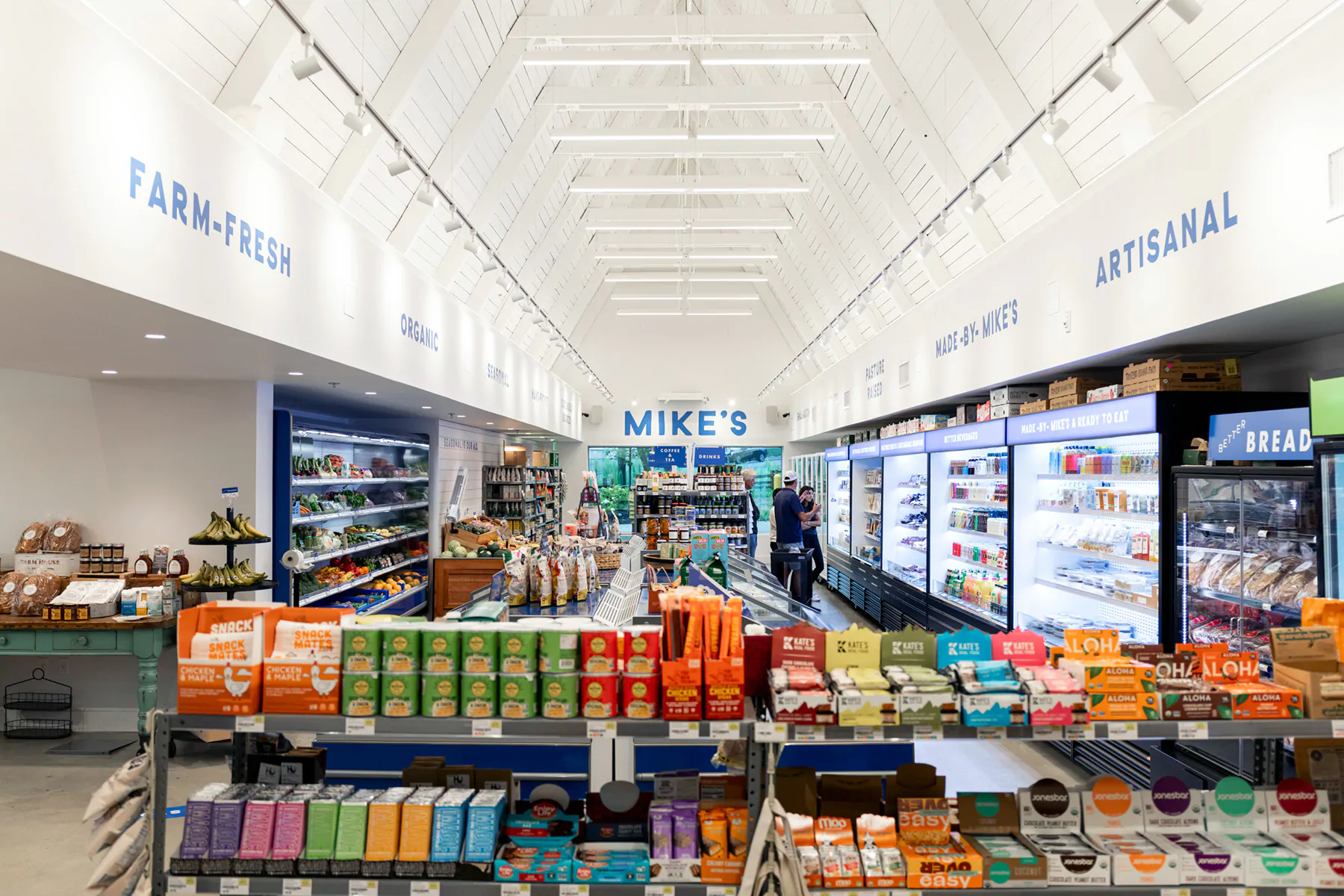 Direct/indirect linear pendant lights illuminate a grocery store while highlighting the architecture of a peaked roof.
