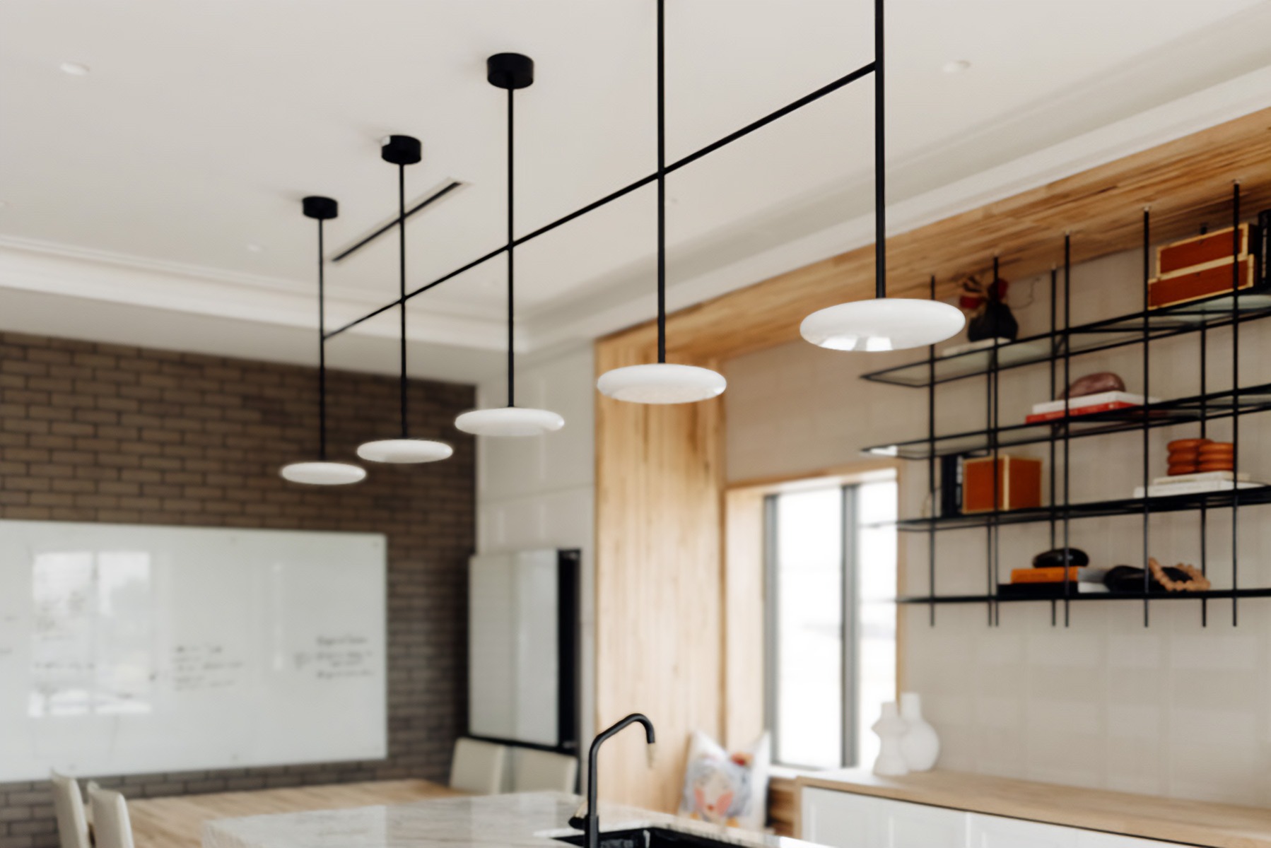 A 5-light pendant light hangs over the HBHQ office kitchen island, providing task lighting, with linear recessed and round recessed lights affording general lighting