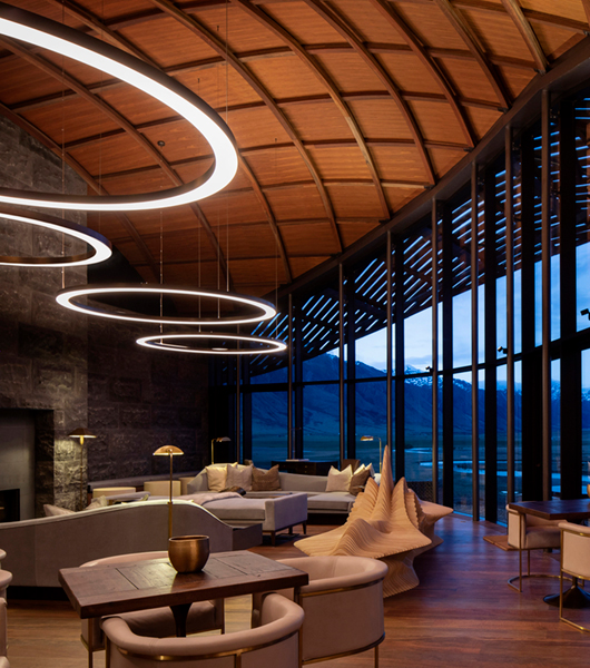 Four oversized ring pendant lights with different diameters hang in the great hall of the Lindis Lodge, providing soft ambient lighting at dusk