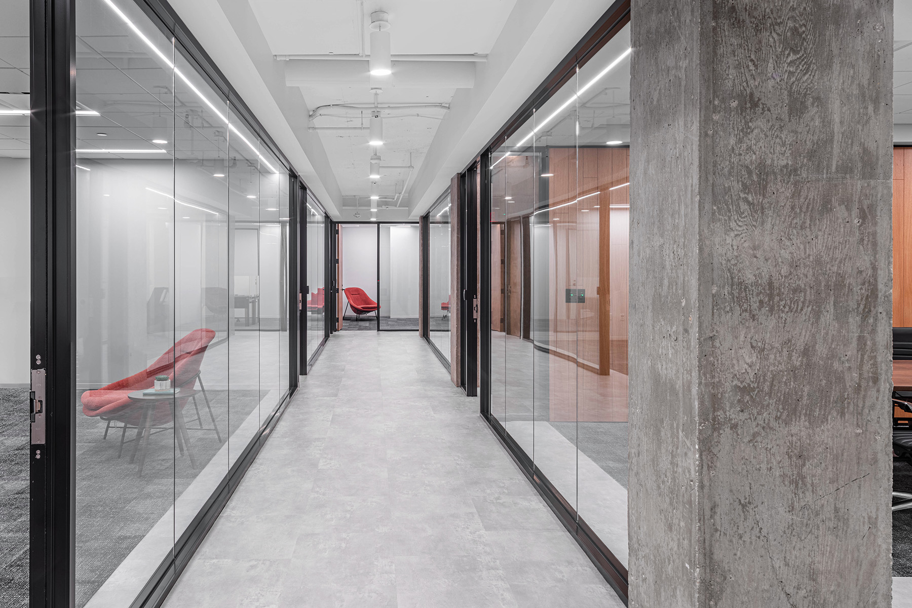 White cylinder pendant downlights line a corridor in a speculative suite office, reflecting light off diffused flooring.