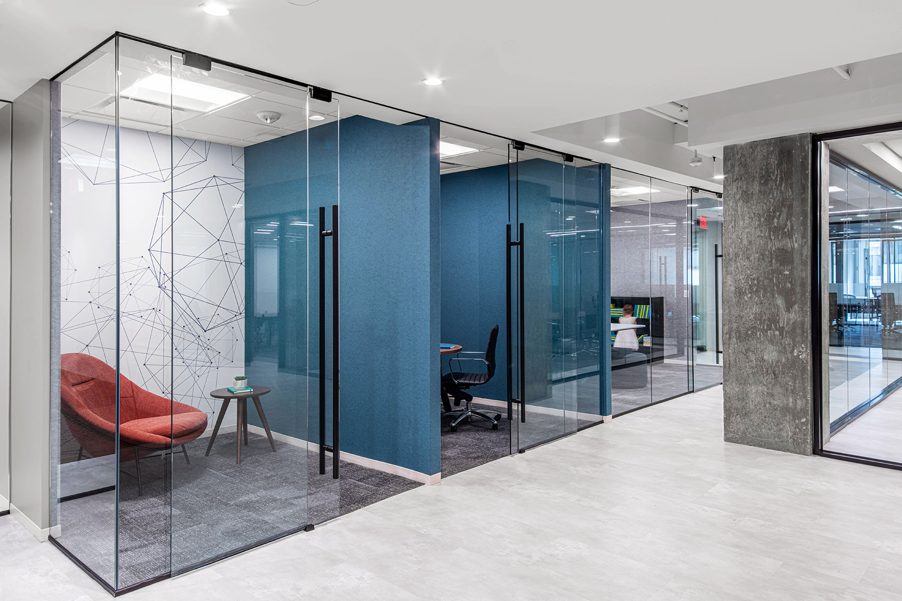 White cylinder pendant lights line a hallway outside glass-fronted work areas at the 2000 M Street Speculative Suites.