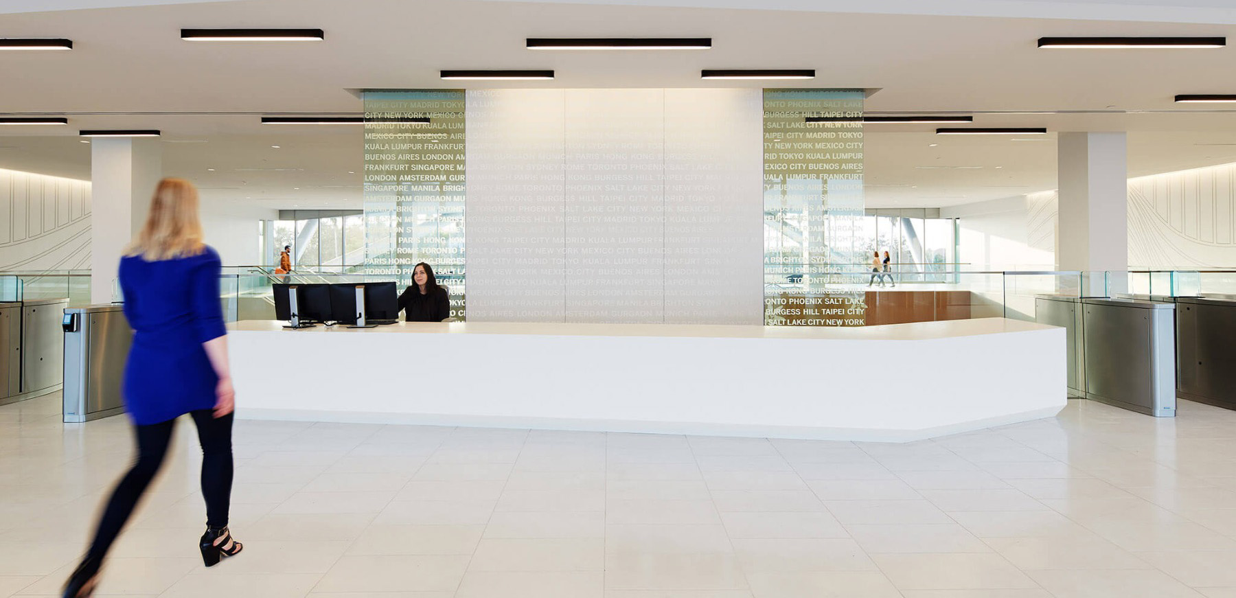 Black LED linear ceiling lights offer general lighting and aesthetic contrast against an office lobby’s cream ceiling.