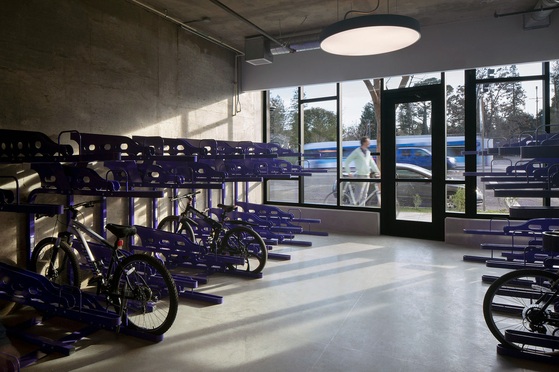  Flush mount disk lights balance with natural light through the front windows of a bicycle storage space at Wilton Court Apartments in Palo Alto, California.
 