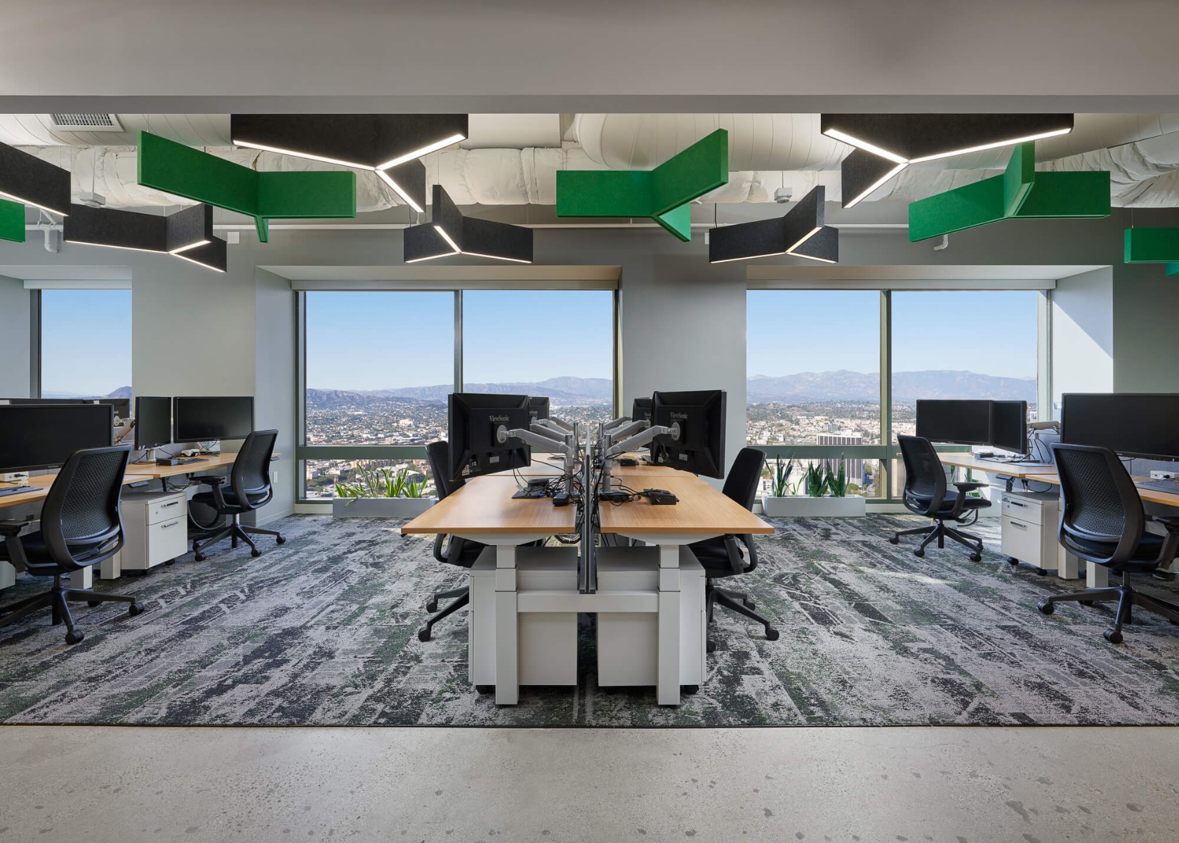 Y-shaped acoustic lighting covered in recycled polyester green and black felt hang over workspaces in an open floor plan office, reducing noise and echo for workers 